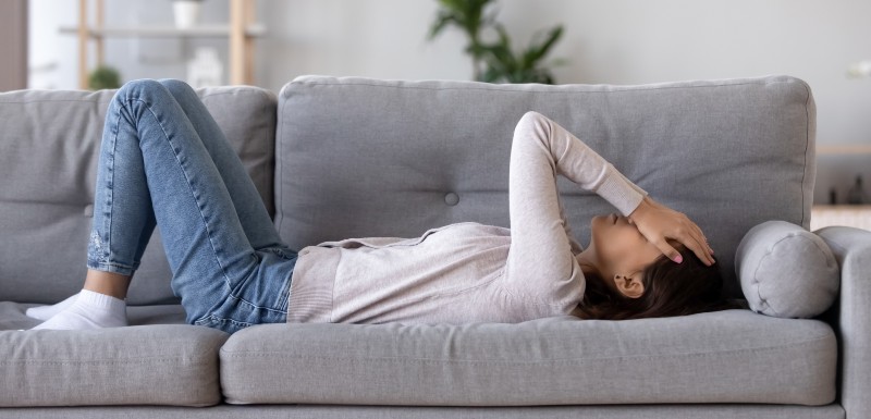 Femme allongée sur son canapé les mains sur le visage