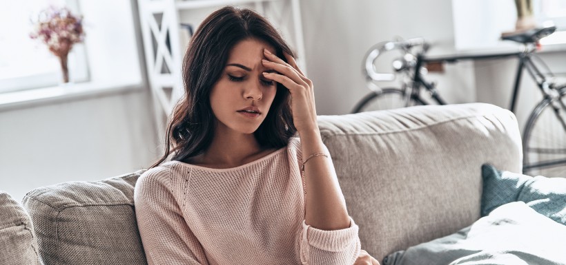 femme dans son canapé qui a mal là la tête